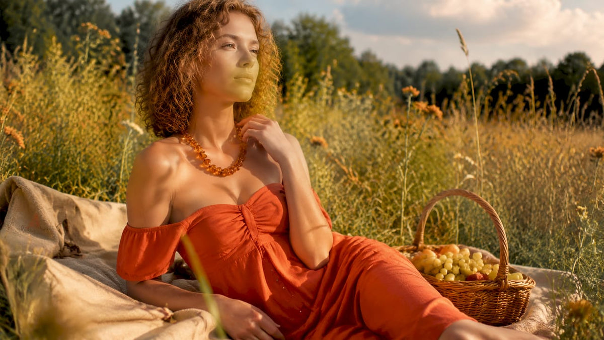 Woman wearing amber necklace against skin in garden