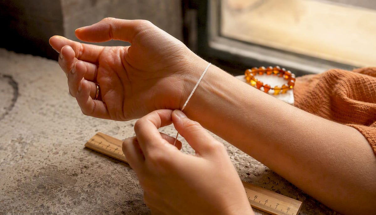 Hands measuring wrist with string and ruler